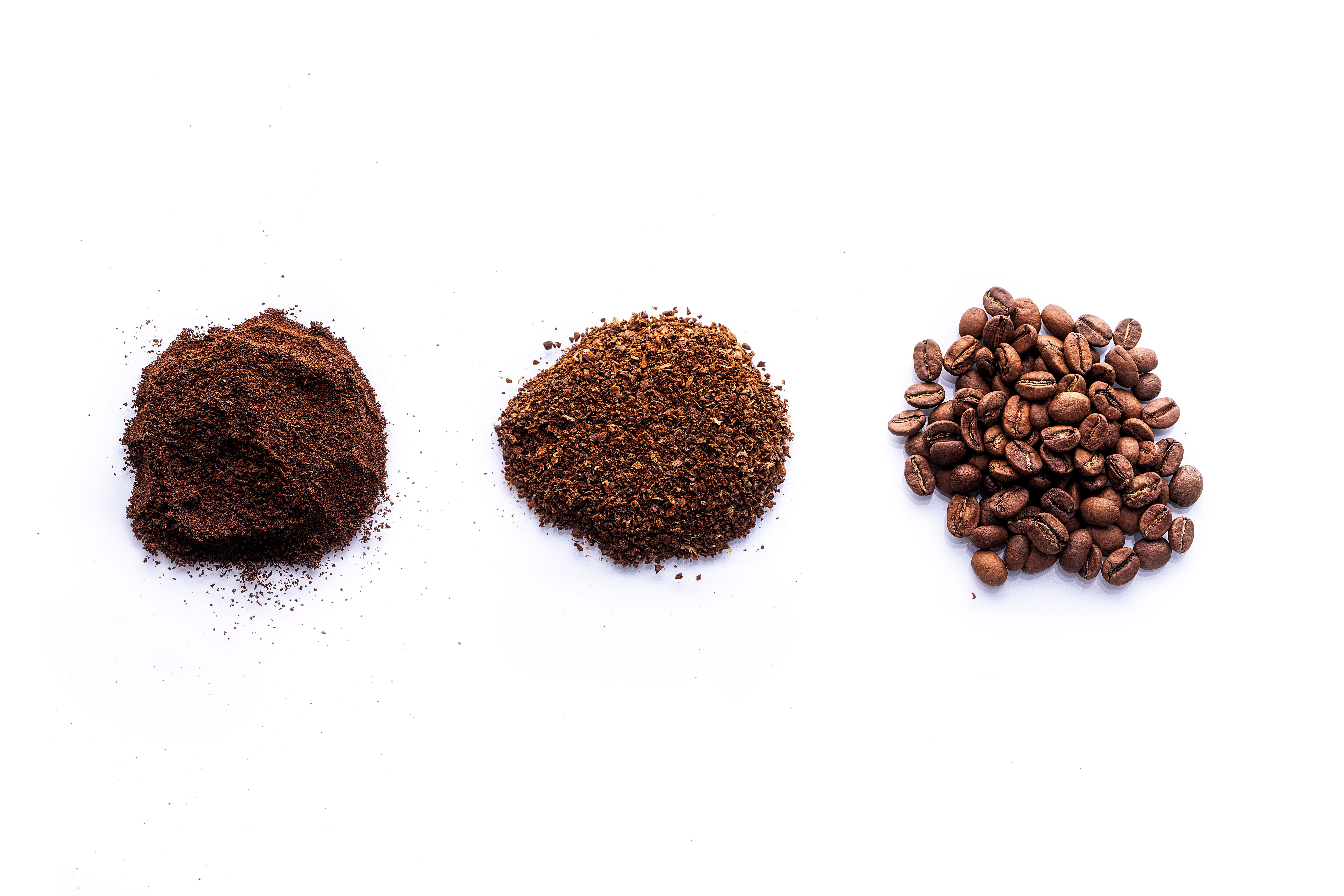 3 mounds of ground coffee on white background from coarse to fine
