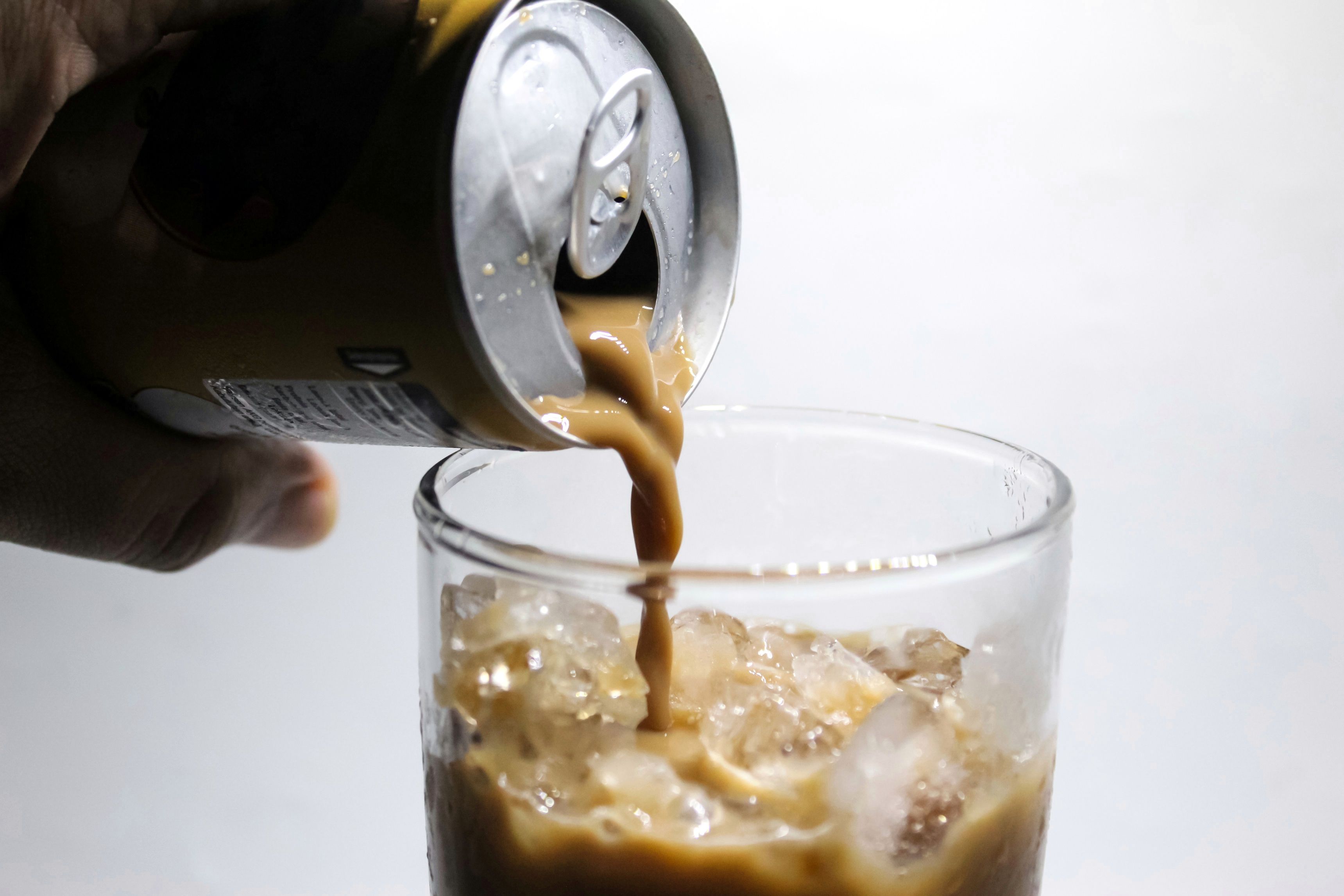 Can of ready to drink coffee being poured into glass over ice