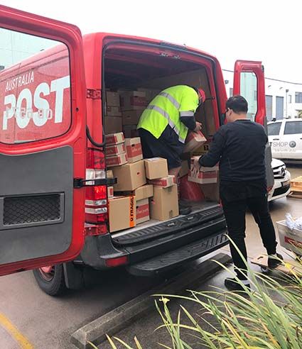 Image of two people unloading a red Australia Post van